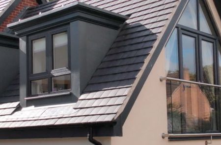 A top of a white home with a tiled roof and french casement windows.